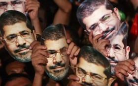 Members of the Muslim Brotherhood and supporters of deposed Egyptian President Mursi hold up masks of him as they gather at the Rabaa Adawiya square, in Cairo