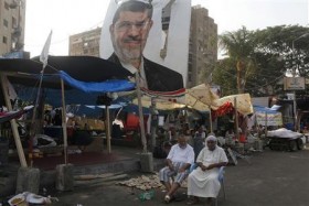 Supporters of deposed President Mohamed Mursi sit near a poster depicting Mursi around the Raba El-Adwyia mosque square in Cairo