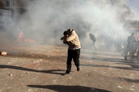 A protester runs from tear gas mask thrown by police on protesters during clashe
