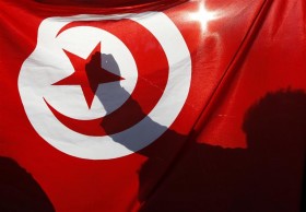 Tunisian people living in France demonstrate behind the Tunisian national flag during a protest in Marseille