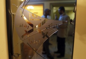 File photo of members of the Muslim Brotherhood speaking behind a door with shattered glass at the Muslim Brotherhood headquarters in Cairo