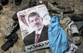 A poster of deposed Egyptian President Mursi lies amid the debris of a cleared protest camp outside the burnt Rabaa Adawiya mosque in Cairo